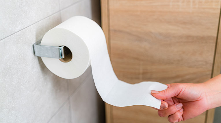 a hand pulls on a roll of toilet paper