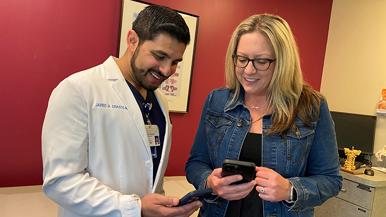 Jared Crasto, MD, and Q102's Jennifer Fritsch look at their cell phones.